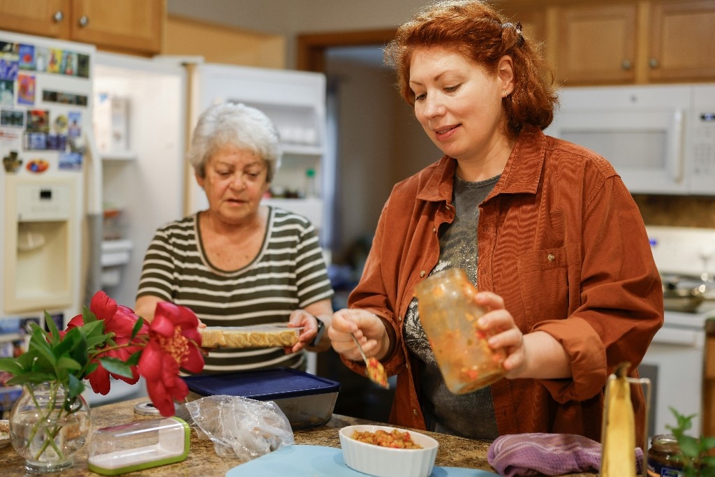 Mother and adult daughter preparing food together in a kitchen