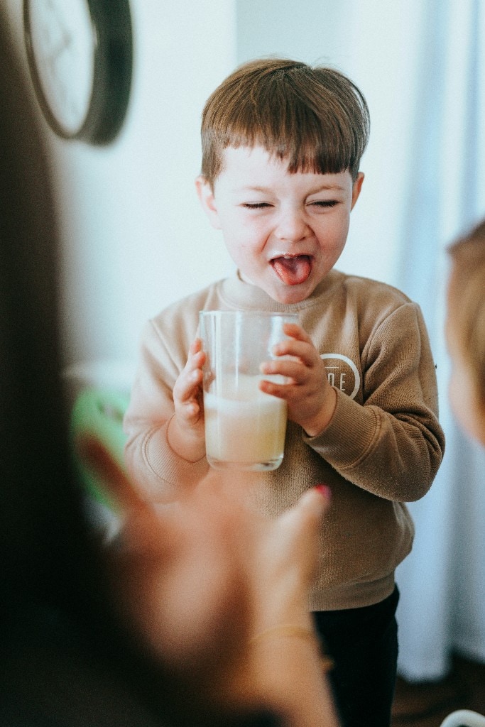Young boy laughing while holding a glass of milk